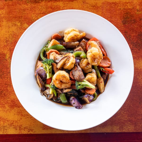 Shrimp and mixed vegetables stir-fry with broccoli, bell peppers, carrots, and eggplant in a dark sauce.